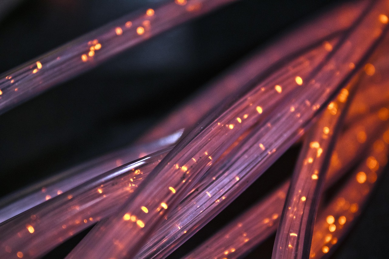 Glowing orange points of light travelling along bundled fibre-optic strands against a dark background