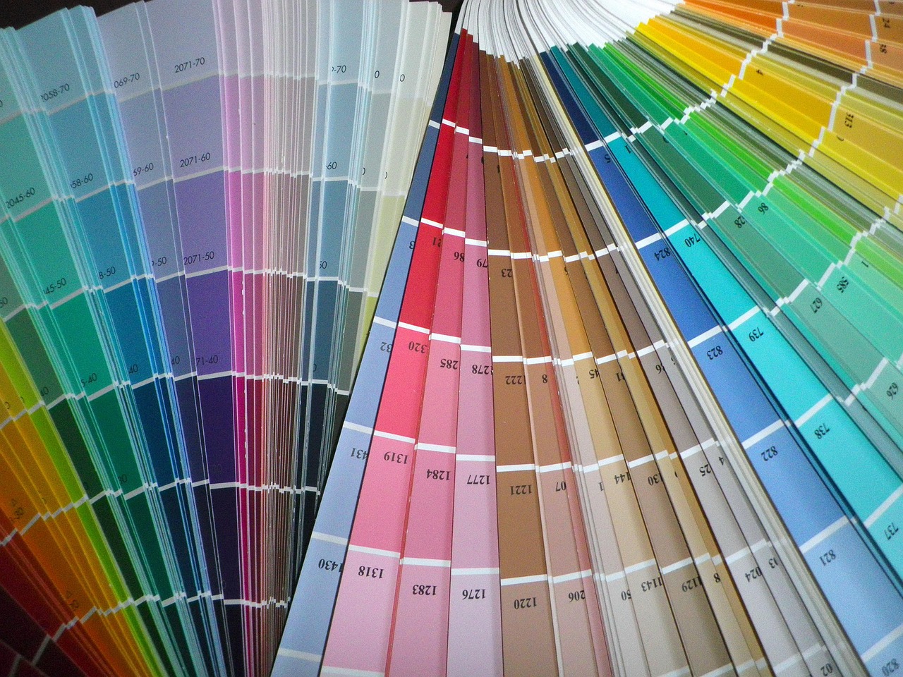 A fan of paper paint swatches spread open, each strip printed with a colour code