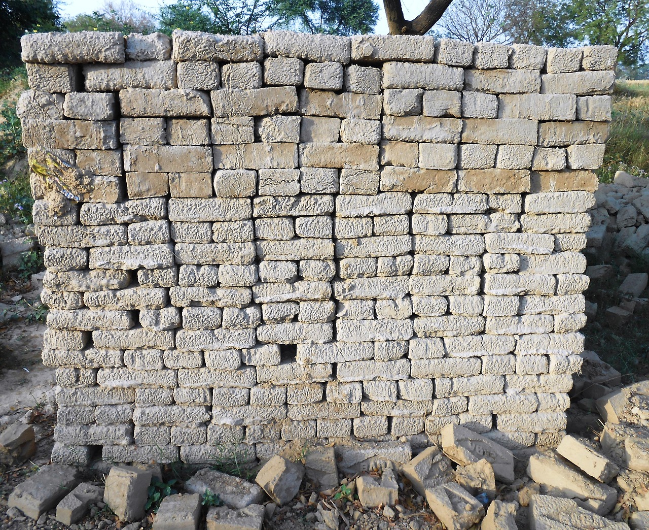 A free-standing dry-stone wall of pale roughly-squared limestone blocks, its courses irregular and unaligned, with rubble at its foot