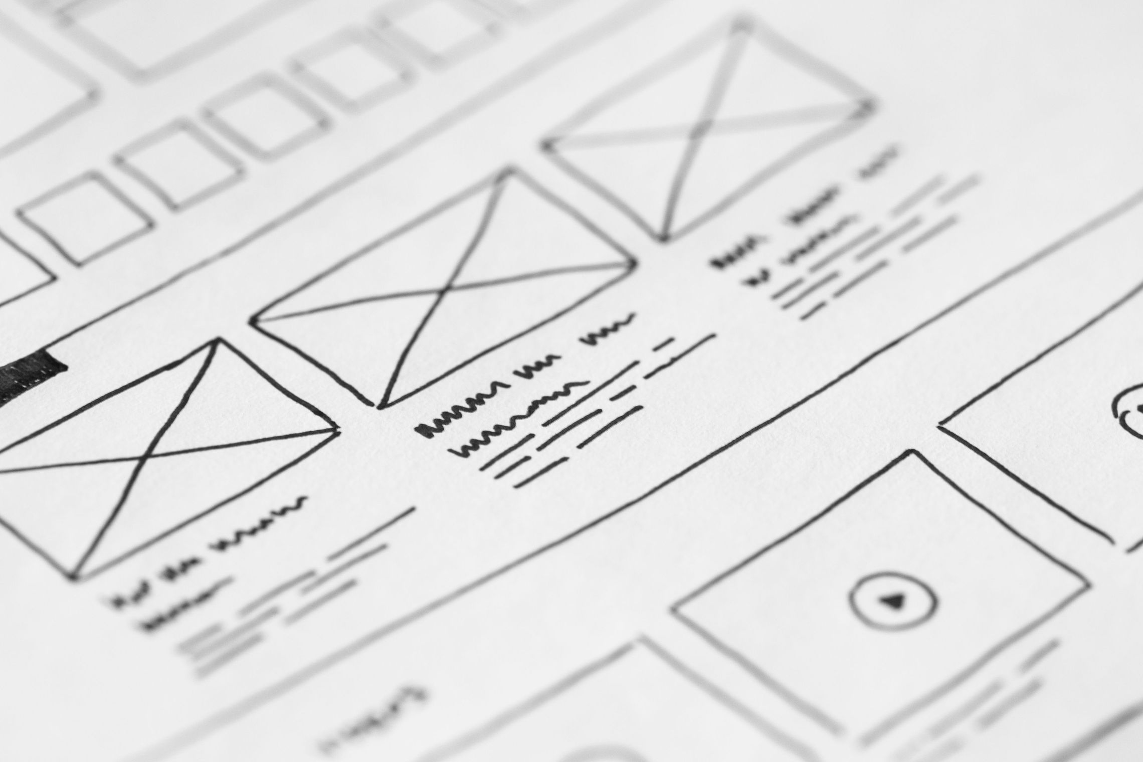 A hand-drawn wireframe on paper, with crossed rectangles standing in for images and ruled lines for body text