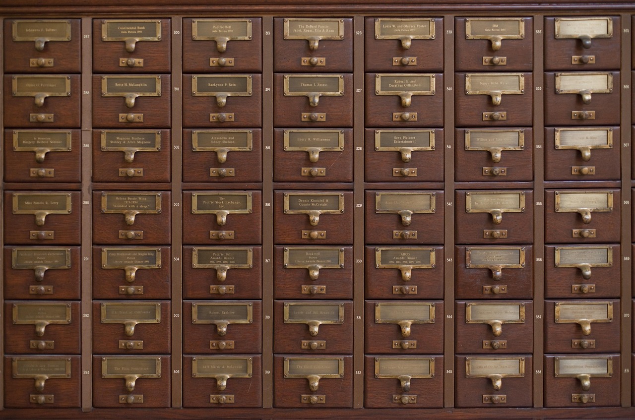 A wall of wooden card catalogue drawers with brass label holders and handwritten numbers