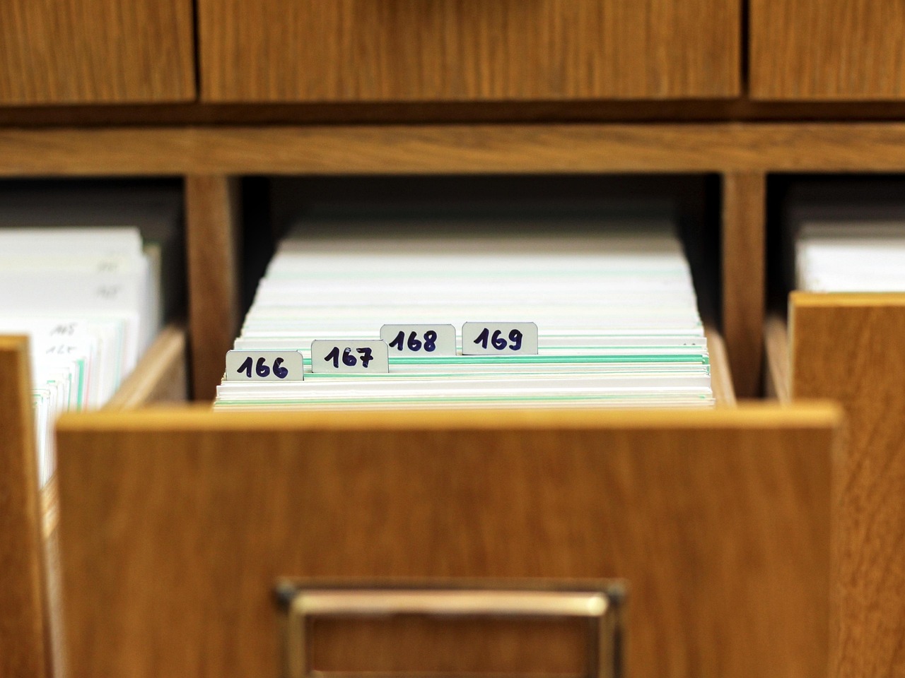An open drawer of index cards with dividers numbered 166 to 169. An IndexedDB index is exactly this: a second ordering of the same records, kept so you can look them up by something other than their key.