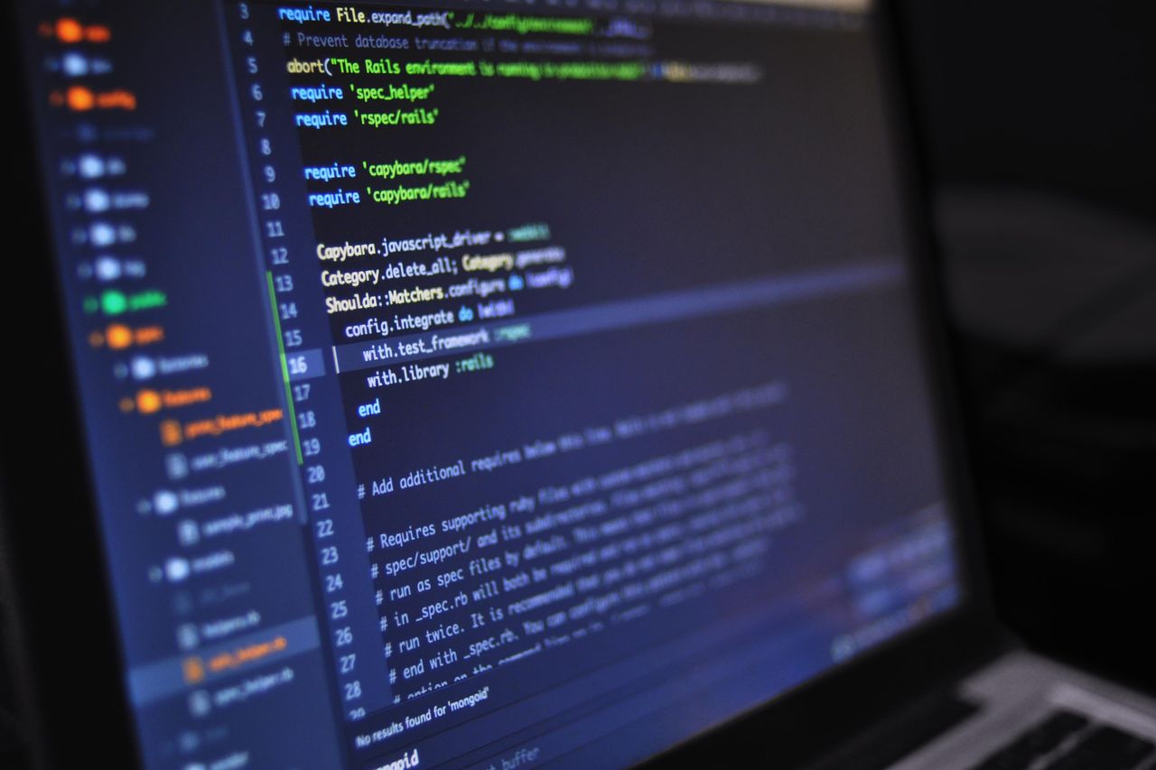 Close-up of a dark-themed code editor on a monitor, showing Ruby configuration code with green and white syntax highlighting, a file tree on the left and line numbers on the right