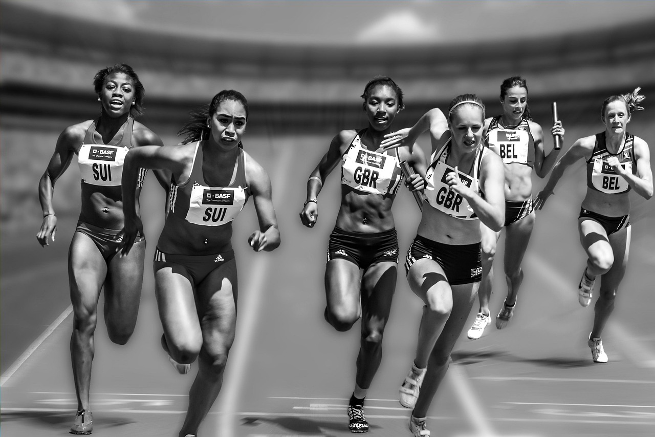 Relay sprinters on a track passing the baton from one runner to the next