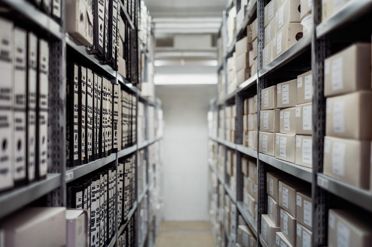 Ein schmaler Archivgang mit Regalen voller beschrifteter Aufbewahrungsboxen und Ordner
