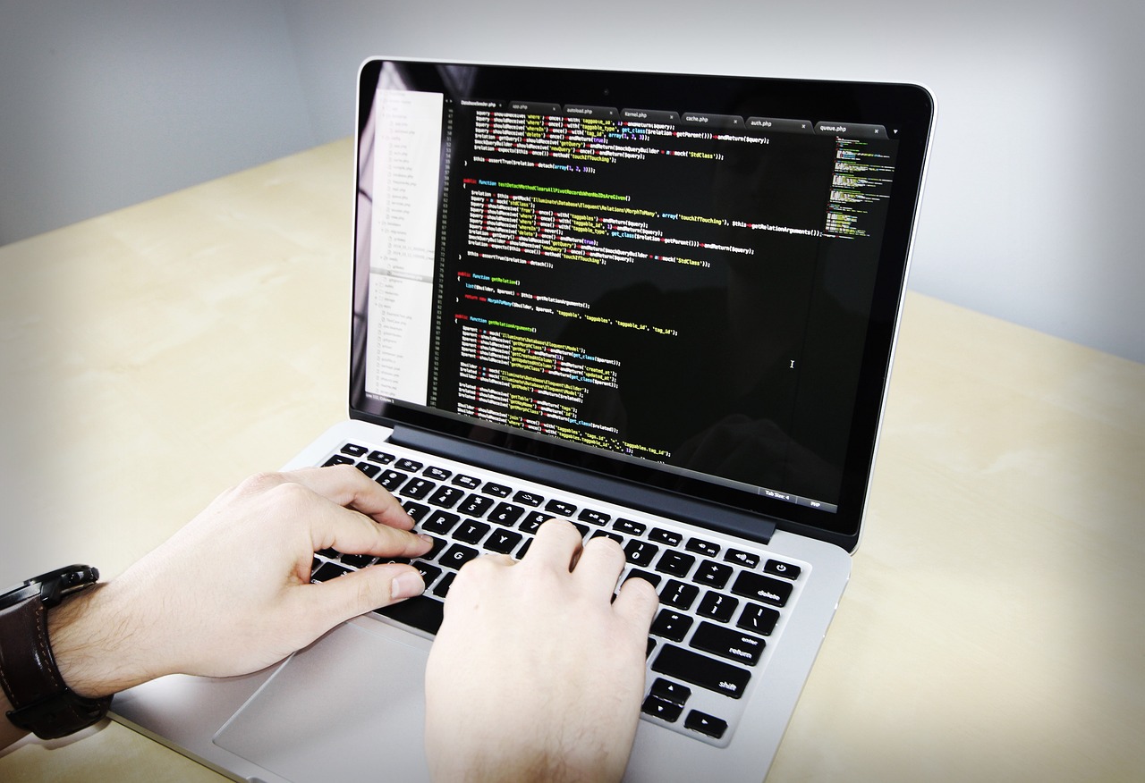 Hands typing on a laptop displaying PHP source code in a code editor