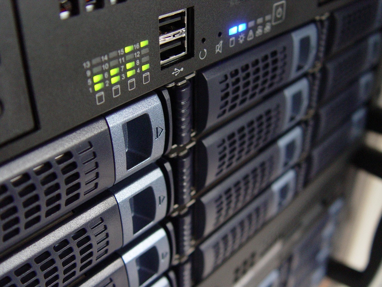 Primer plano de servidores de montaje en rack apilados mostrando LED de estado, puertos USB y bahías de disco en un armario