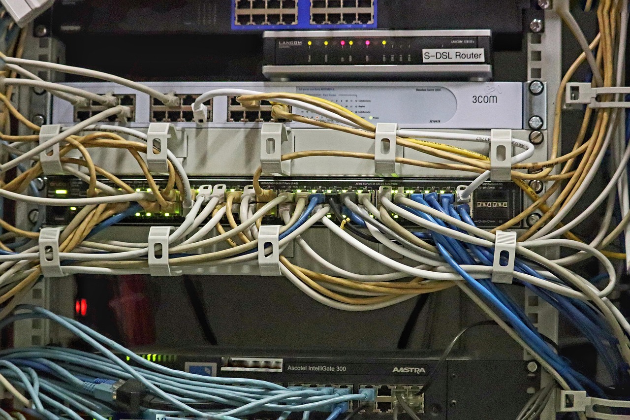 Cables de red agrupados conectados a switches y routers montados en rack dentro de un armario de servidores