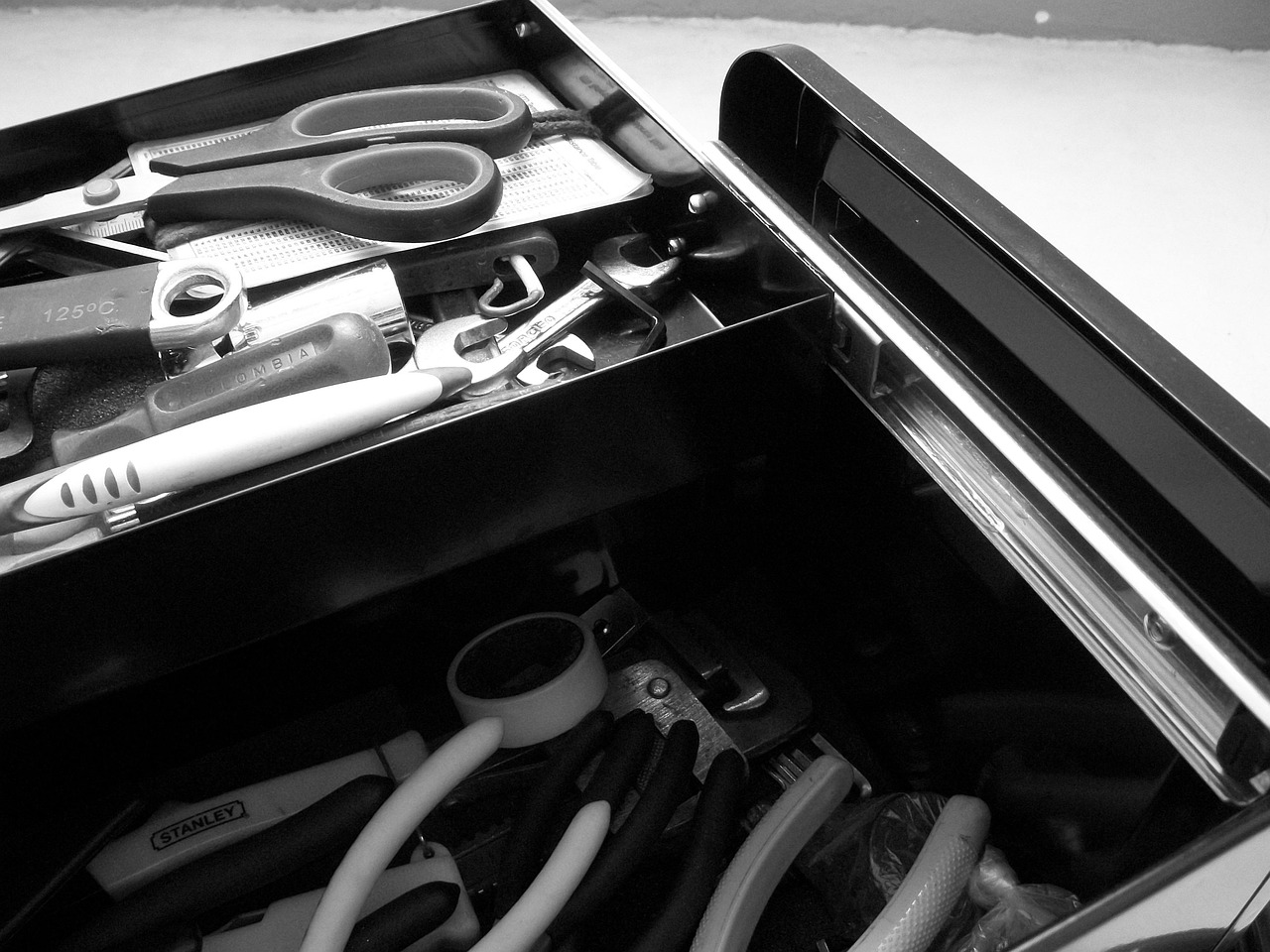 An open metal toolbox with neatly organised tools in separate compartments